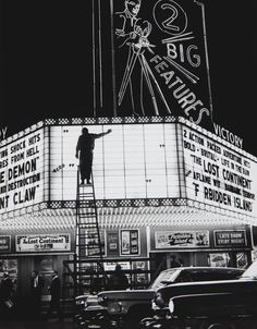 a man standing on top of a ladder in front of a movie theater