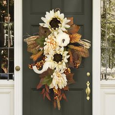 a front door decorated for fall with white pumpkins and sunflowers on it