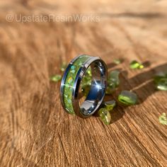 a wedding ring with green moss growing out of it on top of a wooden table