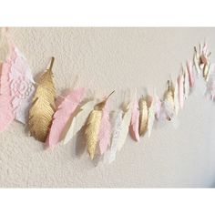 some pink and gold feathers are hanging on the wall