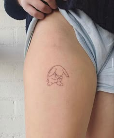 a person with a small tattoo on their thigh, holding onto the side of her leg