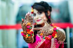 a woman holding up her hands with hendi tattoos on it's palms and wearing colorful bracelets