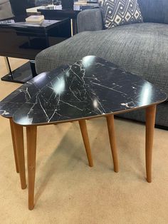 a black marble coffee table sitting on top of a floor next to a gray couch