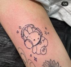 a tattoo with a teddy bear and sunflower on the left arm, in black ink