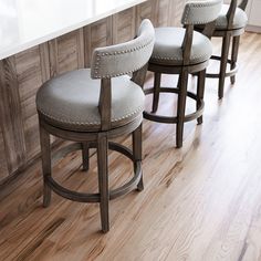 three stools in a kitchen with wood paneling and white counter tops on the island