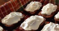 there are many small pieces of bread with white icing on them, sitting on a plaid cloth