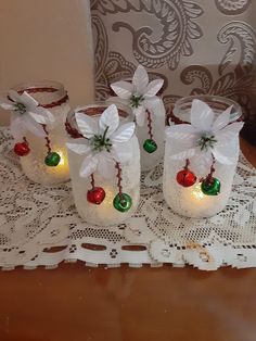 four mason jars decorated with lights and bows on a lace doily tablecloth covered table