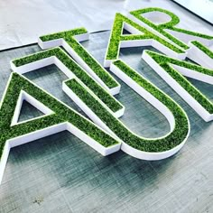 the letters are made out of grass and have been cut into smaller letters to spell out what's inside