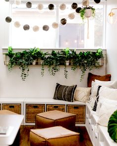 a window seat with plants hanging from it's windowsill and storage boxes underneath