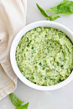 a white bowl filled with guacamole on top of a table next to a napkin