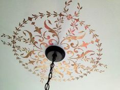 a lamp hanging from the ceiling in front of a wall with an intricate design on it