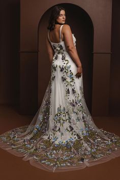 a woman in a white dress with purple flowers on the skirt and her back to the camera