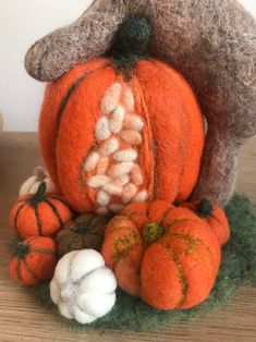 an orange stuffed animal surrounded by pumpkins and cotton balls on a wooden table top