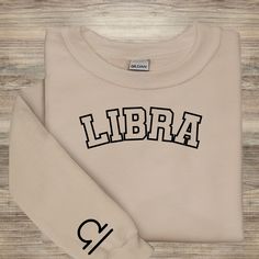 a white sweatshirt with the word libra printed on it, next to a pair of scissors