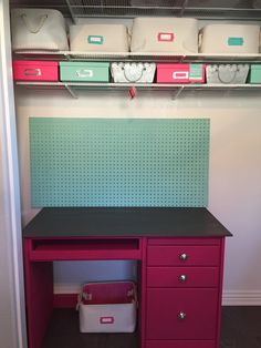 a pink and green desk in a closet with several bins on the wall behind it