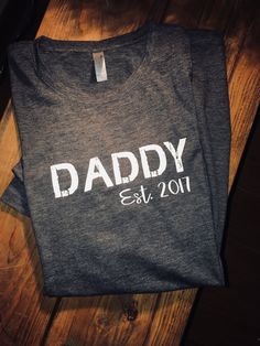 This charcoal tshirt with DADDY in distressed letters and est yr of when he became a dad is simple yet sleek and trendy! Make a great fathers day gift for that special daddy....Modify year no problem just put year in the notes at checkout :) Tshirts are high quality and made up of polyester, cotton and rayon, wash and dry well time after time!! Customizing colors is an option just msg us and we can get it taken care of. Thanks for shopping with us! Dad Fathers Day Gifts, Best Dad Shirt, Papa Shirts, Tshirt Printing Design, Father Shirts, Tshirt Printing, Fathers Day Presents, Presents For Dad, Father's Day T Shirts