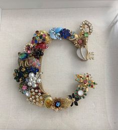 the letter c is made up of many different types of jeweled objects, including brooches and pearls