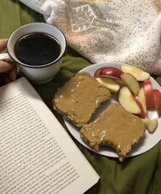 a person is reading a book and eating some food with an apple on the side