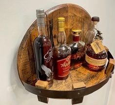 several bottles of liquor are sitting on a wooden barrel shelf in the corner of a room