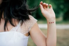 a woman with a heart tattoo on her left arm and right hand in the air