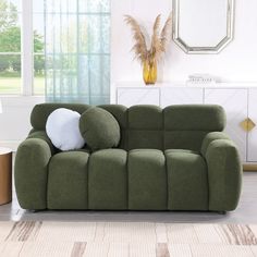 a green couch with pillows on it in a living room