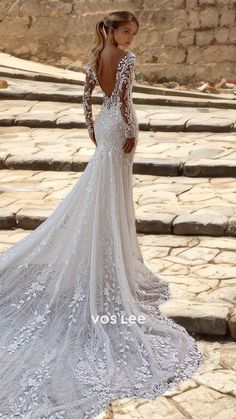 a woman in a white wedding dress standing on some steps with her back to the camera