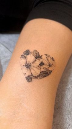 a woman with a tattoo on her arm has flowers in the shape of a heart