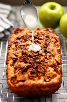 a piece of cake sitting on top of a cooling rack next to some green apples