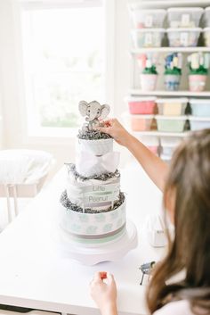 a woman decorating a three tiered cake