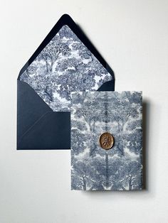 an envelope with a wax stamp on it next to a blue and white patterned card