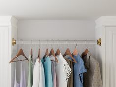 several shirts hanging on hooks in a closet