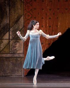 a woman in a blue dress is dancing on stage