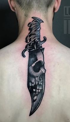 a man with a tattoo on his back has a knife in the shape of a skull