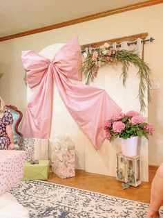 a woman sitting on a couch in front of a wall decorated with pink bows and flowers