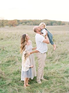 a man and woman holding a child in their arms while standing in the middle of a field