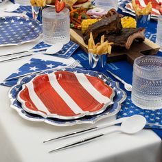 an american flag table setting with plates, silverware and utensils on it