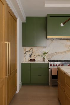 a kitchen with green cabinets and marble counter tops, along with a stove top oven