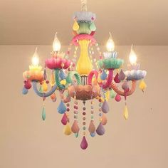 a chandelier that has candles on it and colorful decorations hanging from the ceiling