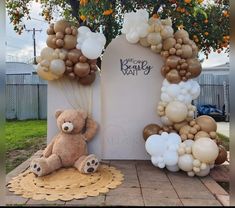 a teddy bear sitting on top of a rug next to balloons in the shape of letters