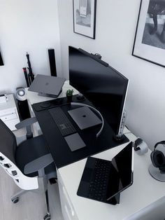 a desk with a laptop, monitor and speakers on it in a white office space