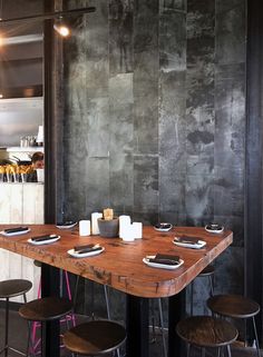 a wooden table with four stools in front of it and a chalkboard wall behind it