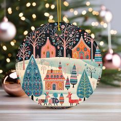 an ornament hanging from a christmas tree decorated with colorful houses and deers