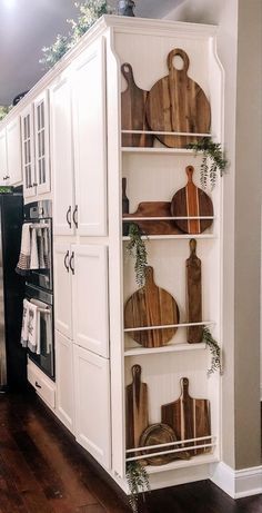 a kitchen with white cabinets and wooden cutting boards on the top shelf, in front of an oven