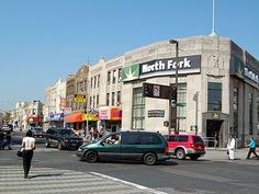 people walking across the street in front of a store