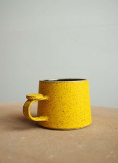 a yellow coffee cup sitting on top of a table