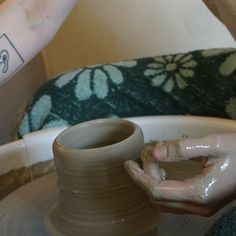 a person is making a vase on a potter's wheel with one hand and the other