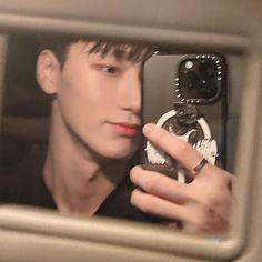 a man taking a selfie with his cell phone in front of him and looking into the mirror