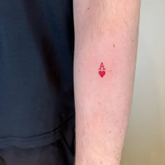 a small red heart tattoo on the left inner arm, with an arrow in the middle