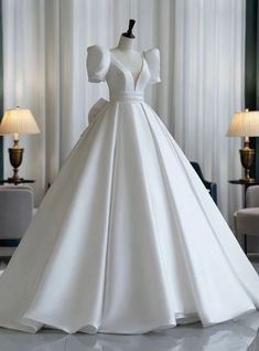 a white wedding dress on a mannequin in a room with lamps and curtains