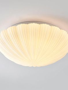 a white ceiling light that is on top of a gray wall and has a shell like design